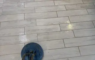 Rotary scrubber cleaning a grey wood-look tile floor