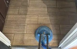 Rotary scrubber cleaning a wood-look tile floor in a rental home