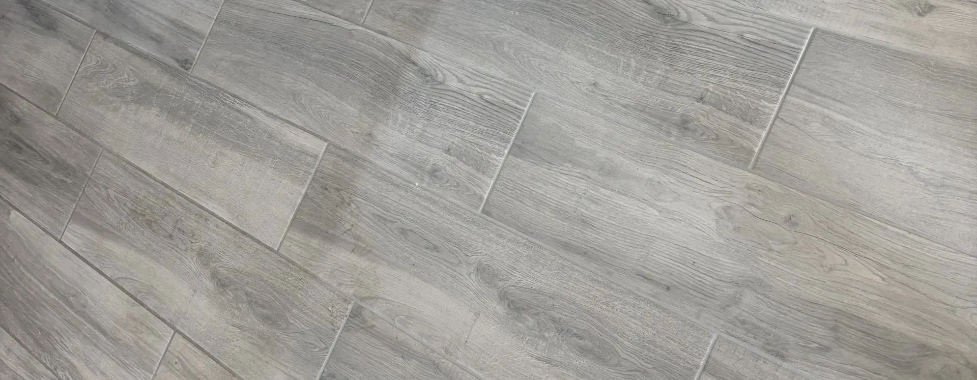 Grey wood-look plank tile floor before professional cleaning